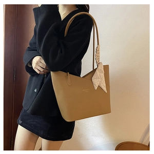 Detail of camel lychee leather tote bag with silk scarf handle and golden logo