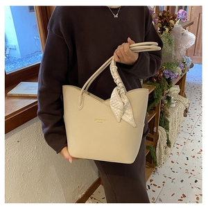 Close-up of cream beige crossbody bag with textured leather and floral silk scarf detail