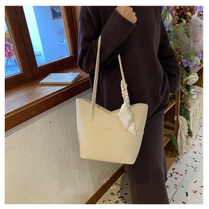 Close-up of beige lychee texture tote bag with silk scarf and gold lettering detail