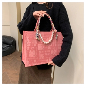 Detail van de roze bruidstas met dubbele gelukspatronen en decoratie van parelhandvat