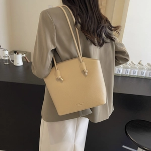 Elegant beige pebbled leather bucket tote bag with long shoulder straps and knot details