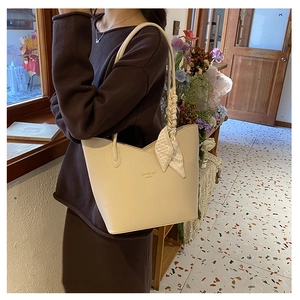 Close-up of cream white leather tote bag with printed silk scarf and gold logo detail