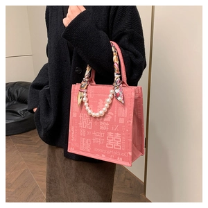 Detail van roze draagtas met parelketting, zijden sjaal aan handvat en Double Happiness-print