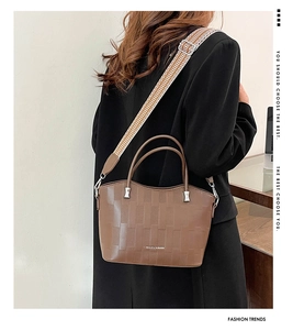 Dettaglio borsa shopper marrone a scacchi con scritte moda e tracolla a fantasia