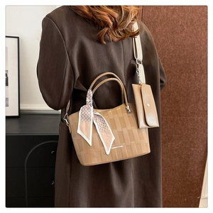 Dettaglio borsa a mano intrecciata marrone chiaro con foulard e mini pochette coordinata