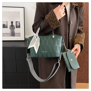 Dettaglio della borsa tote verde scuro goffrata con foulard e tracolla a righe