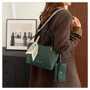 Dettaglio della borsa tote verde scuro con motivo intrecciato, foulard e mini pochette