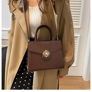 Détail du sac à main en cuir marron foncé avec fermoir floral doré élégant