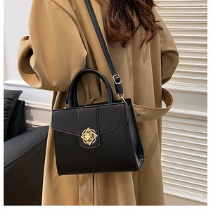 Vue latérale d'un sac à main carré en cuir noir avec boucle dorée porté avec un trench