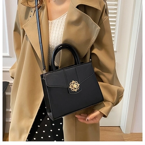Détail du sac à bandoulière noir avec fermoir rotatif en forme de rose dorée sur le rabat
