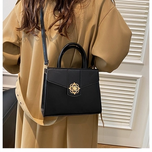 Détail du petit sac carré noir avec fermoir floral doré et bandoulière réglable