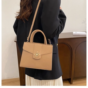 Détail du sac à main carré beige avec fermoir fleuri doré et texture en cuir raffiné