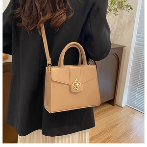 Détail du sac bandoulière carré kaki avec boucle florale dorée et fermeture à rabat