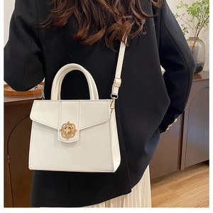 Petit sac carré blanc avec fermoir fleur dorée porté par un mannequin élégant