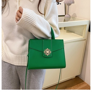 Détail du sac bandoulière vert avec boucle florale dorée et similicuir lisse élégant