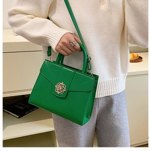 Détail du sac à main en cuir vert vif avec fermoir fleuri doré et poignée chic