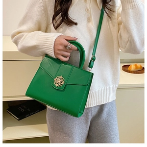 Détail du sac bandoulière vert avec boucle rose dorée et texture cuir raffinée