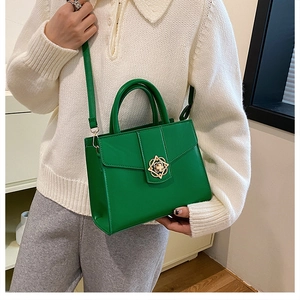 Gros plan d'un sac à main vert vif avec fermoir fleuri doré sur un pull en maille blanc