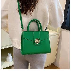 Détail du sac à main en cuir vert vif avec fermoir floral doré porté par un modèle