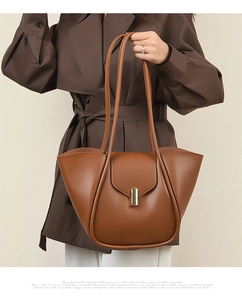 Détail du sac cabas en cuir marron avec structure ailée et boucle dorée chic