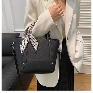 Détail du sac seau en cuir grainé noir avec clous argentés et foulard en soie au manche