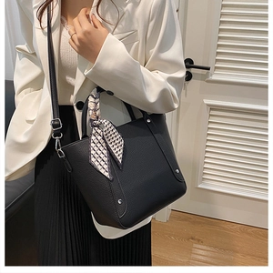 Détail du sac seau noir en cuir avec foulard décoratif à motif sur la poignée