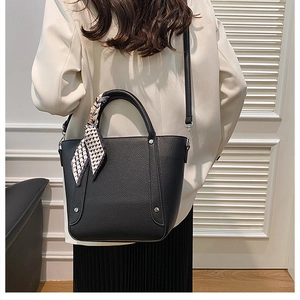 Sac seau en cuir grainé noir avec foulard à carreaux porté par un mannequin vue de dos