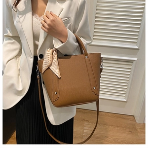 Gros plan sur le sac seau en cuir grainé marron avec foulard décoratif et rivets fins