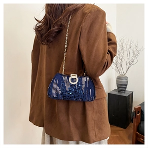 Detailed view of deep blue sequin evening clutch bag with gold chain strap on a model