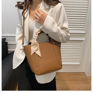 Gros plan sur un sac seau marron en cuir grainé avec foulard en soie à motif géométrique