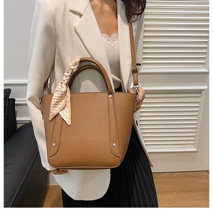 Gros plan sac seau marron à motif litchi avec foulard décoratif et bandoulière amovible
