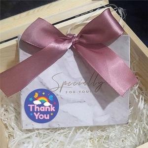 Pink ribbon bow on marble gift box with Thank You sticker and wood wool filling