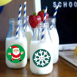 Close-up of Santa and snowflake stickers on a glass bottle with festive decorations