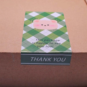 Close-up of cute bear sealing sticker with green grid on a brown paper package