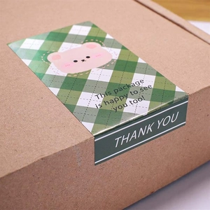 Detail of cute bear sticker on kraft box featuring green checkerboard and thank you text