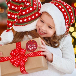 Close-up of a red Merry Christmas sticker on a kraft gift box with festive ribbon decoration