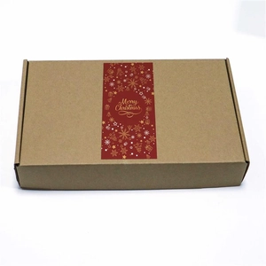 Detail of red Merry Christmas sticker on brown corrugated cardboard gift packaging box