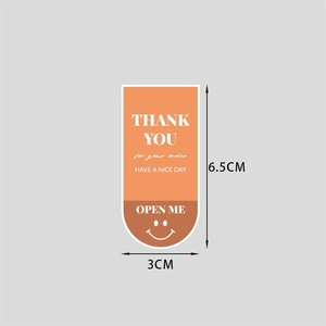 Detail view of U-shaped packaging stickers in orange and brown with 6.5x3cm dimensions