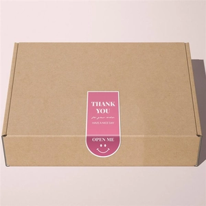 Pink smiley face thank you sticker sealing a brown kraft paper gift box for orders