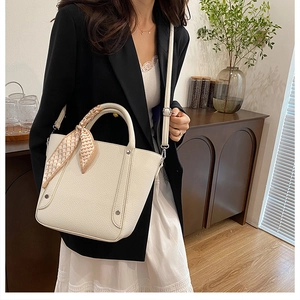 Détail du sac seau crème avec texture litchi et foulard imprimé cœur sur l'anse