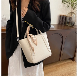Détail du sac seau crème avec texture litchi, poignée en foulard et rivets métalliques