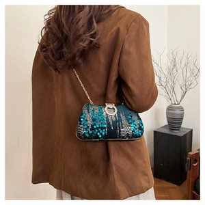 Detailed view of deep teal sequin evening bag with diamond-set lock and gold chain strap