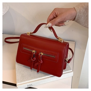 Detailed view of the dark red square handbag with double decorative gold zippers