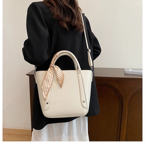 Détail du sac seau blanc crème avec texture cuir grainé et foulard en soie décoratif