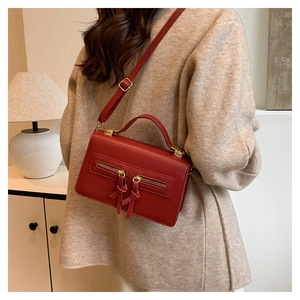 Detail of red vintage leather bag featuring dual gold zippers and adjustable shoulder strap