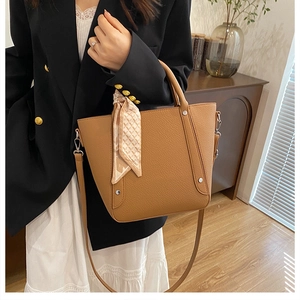 Gros plan d'un sac seau en cuir marron avec foulard en soie décoratif sur l'anse