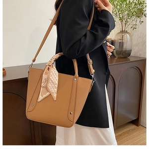 Détail du sac seau marron avec texture cuir grainé et accessoire foulard en soie décoratif