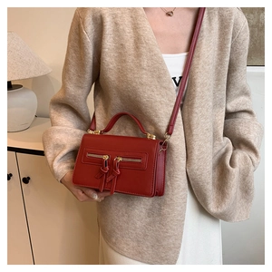 Detailed view of red leather crossbody bag with double zip tassels and gold hardware