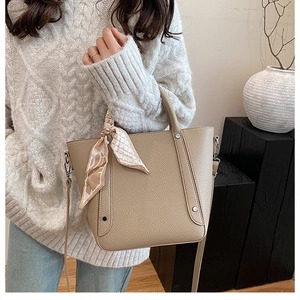 Sac seau beige chic en cuir grainé avec détail de foulard en soie sur la poignée