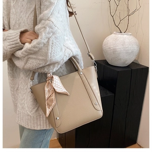 Sac seau en cuir beige avec clous argentés et foulard en soie rose décoratif